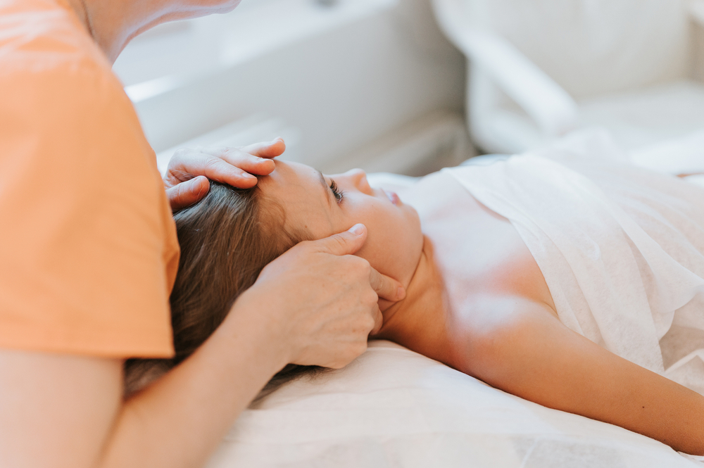 real doctor osteopath hands does physiological and emotional therapy for eight year old kid girl. pediatric osteopathy treatment session. alternative medicine. taking care of the child's health